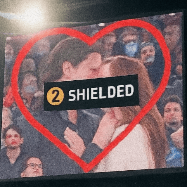 Kiss cam on a stadium screen, the couple's kiss covered by a black SHIELDED bar